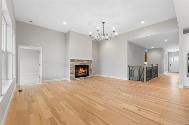 unfurnished living room with baseboards, light wood-style flooring, visible vents, and a notable chandelier