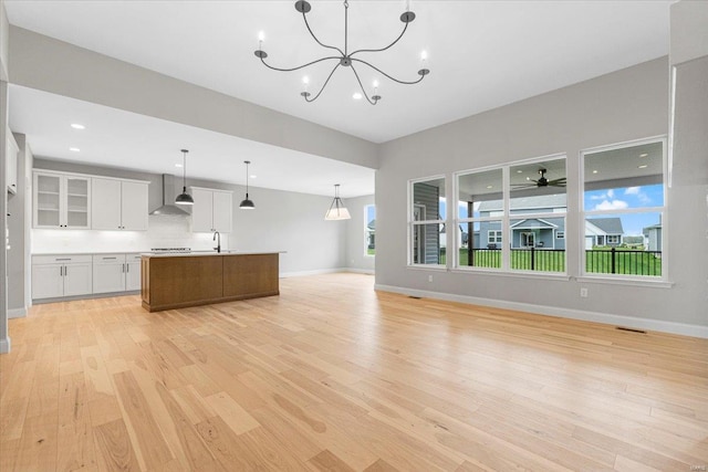 unfurnished living room featuring light wood-type flooring, baseboards, a sink, and recessed lighting