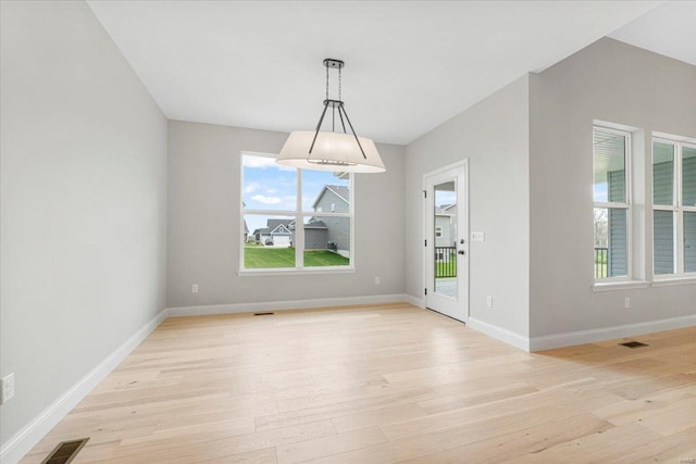 unfurnished dining area with light wood-style flooring, a wealth of natural light, baseboards, and visible vents