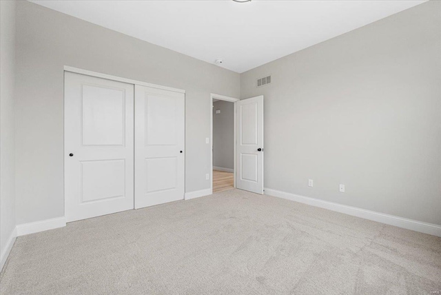 unfurnished bedroom featuring carpet floors, a closet, visible vents, and baseboards