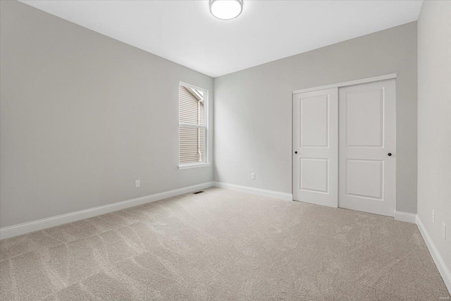 carpeted spare room featuring visible vents and baseboards