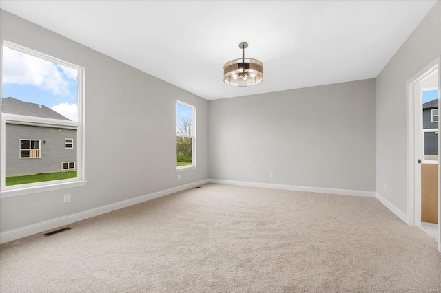 empty room featuring baseboards, visible vents, and light colored carpet