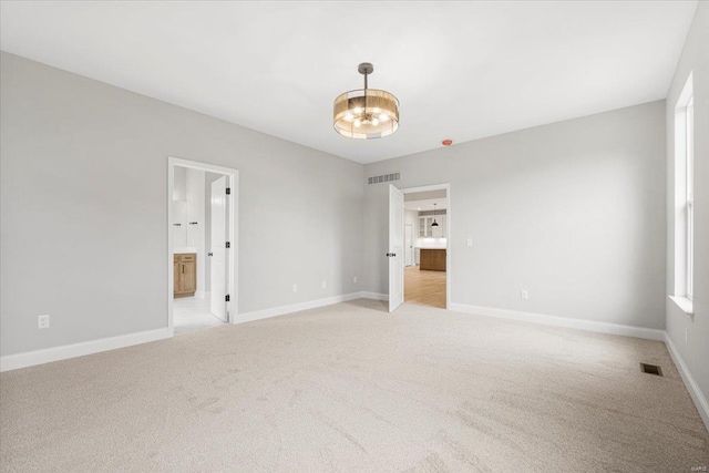 unfurnished bedroom with visible vents, baseboards, light carpet, and an inviting chandelier