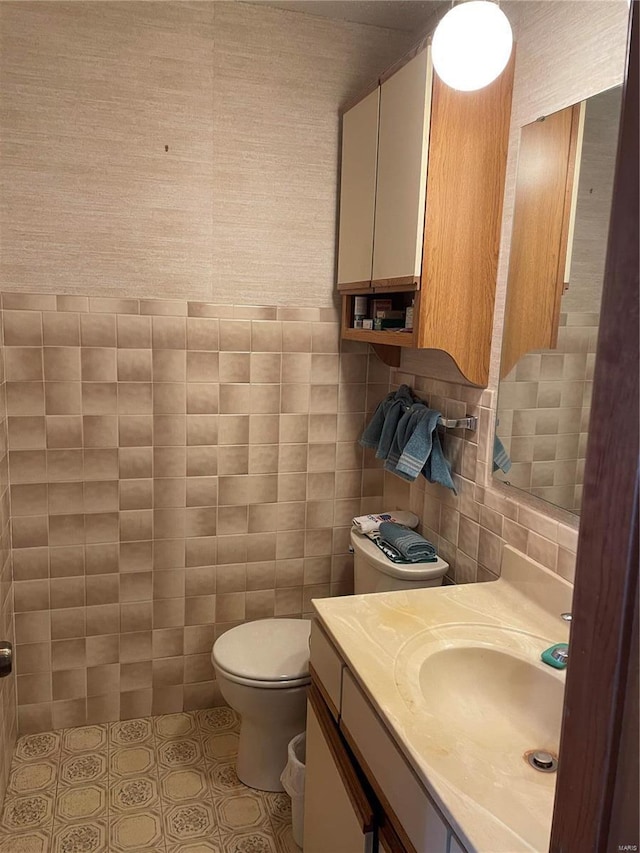 bathroom featuring toilet, tile walls, tile patterned floors, and vanity