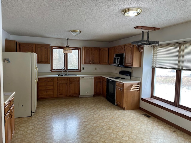 kitchen featuring hanging light fixtures, sink, white appliances, and a textured ceiling