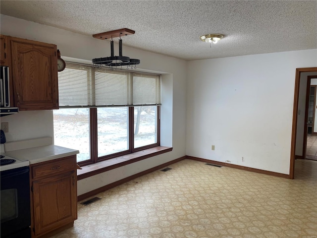 kitchen featuring electric range oven, a textured ceiling, and hanging light fixtures