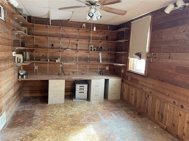 interior space with ceiling fan and wooden walls