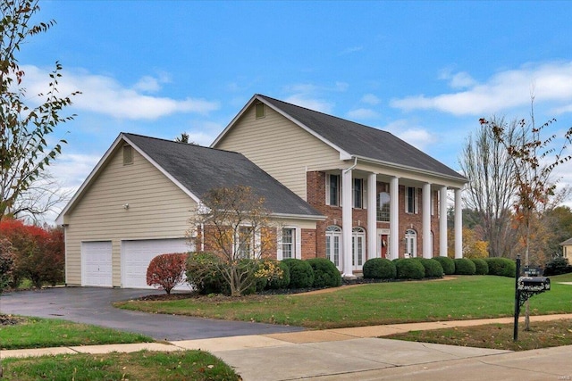 greek revival inspired property with a garage and a front lawn