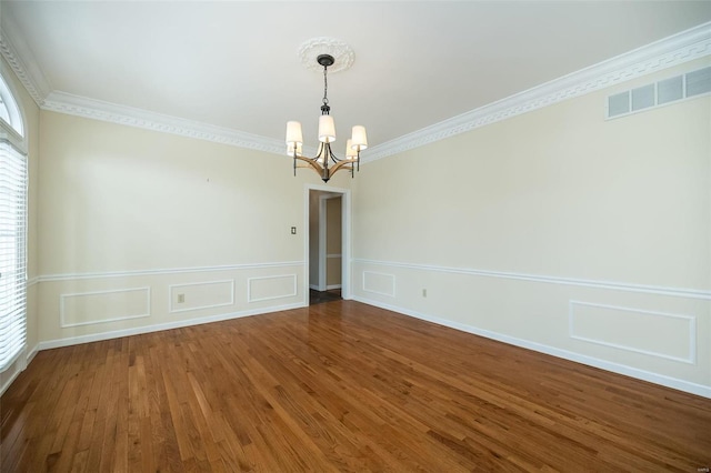 unfurnished room featuring an inviting chandelier, dark wood-type flooring, and ornamental molding