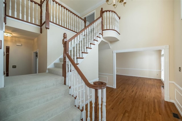 staircase featuring ornamental molding, hardwood / wood-style floors, and a high ceiling