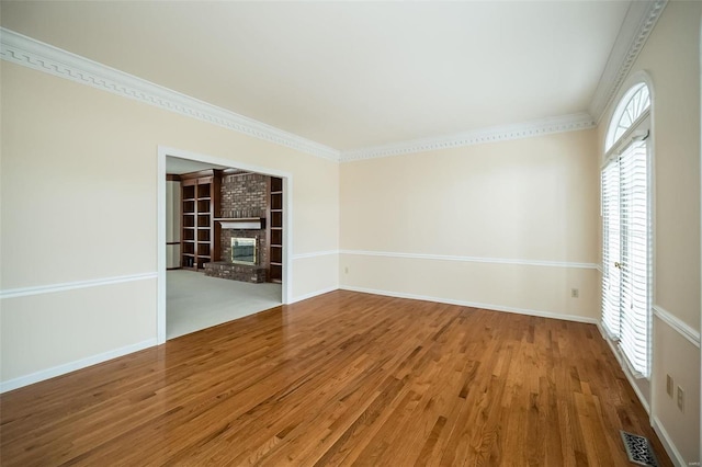 empty room with hardwood / wood-style flooring, crown molding, and a brick fireplace