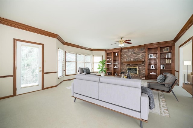 living room with a brick fireplace, crown molding, light colored carpet, and ceiling fan