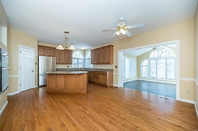 kitchen featuring hanging light fixtures, stainless steel appliances, a center island, and light wood-type flooring