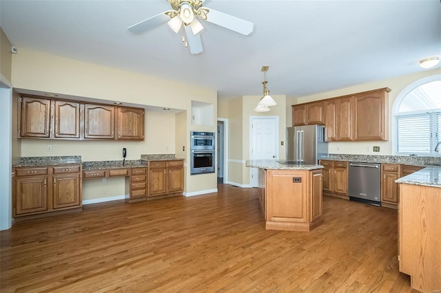 kitchen featuring stainless steel appliances, a kitchen island, dark hardwood / wood-style flooring, and decorative light fixtures