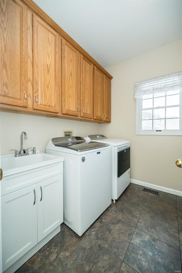 clothes washing area featuring cabinets, sink, and independent washer and dryer