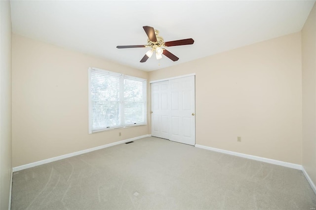 unfurnished bedroom with ceiling fan, light colored carpet, and a closet