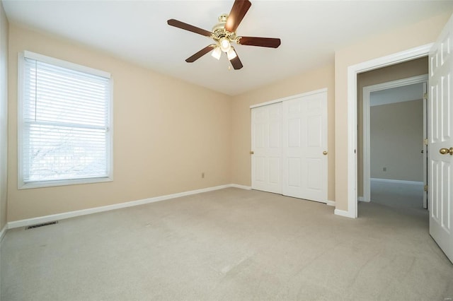 unfurnished bedroom with light carpet, a closet, and ceiling fan