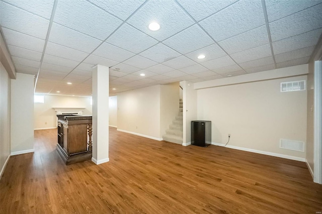 basement with a paneled ceiling and wood-type flooring