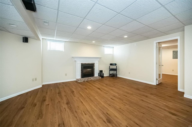 basement featuring hardwood / wood-style flooring, plenty of natural light, a paneled ceiling, and a fireplace