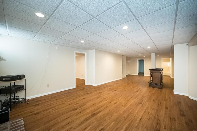 basement featuring a paneled ceiling and wood-type flooring