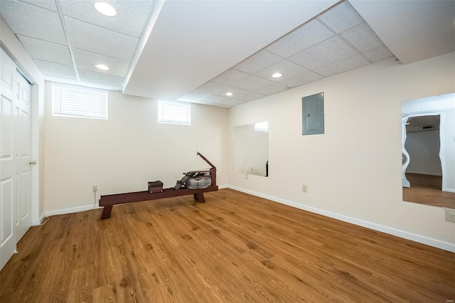 basement with wood-type flooring, a drop ceiling, and electric panel