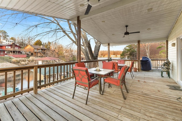 wooden deck featuring area for grilling, ceiling fan, and a water view