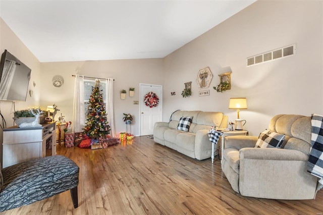 living room with light hardwood / wood-style floors and vaulted ceiling