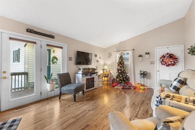 living room with light hardwood / wood-style floors and vaulted ceiling