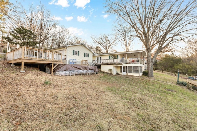 back of house with a sunroom, a deck, and a lawn