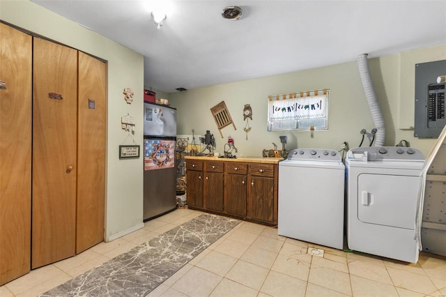 clothes washing area featuring electric panel, cabinets, light tile patterned floors, and washing machine and dryer