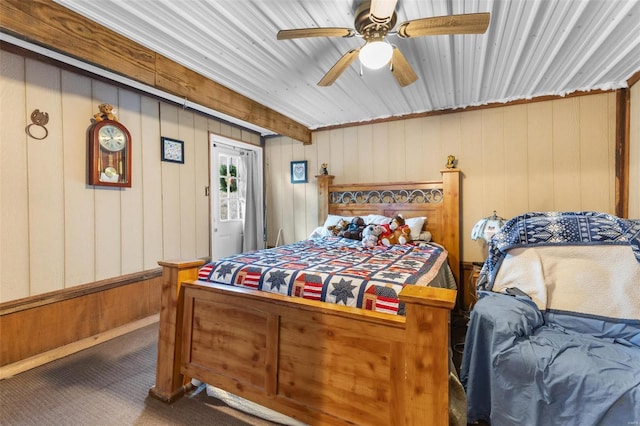 carpeted bedroom with ceiling fan and wooden walls