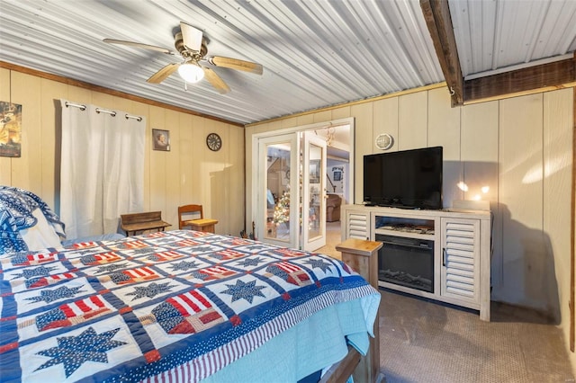 carpeted bedroom featuring beam ceiling, ceiling fan, and wooden walls