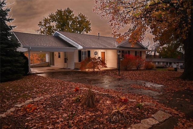 back house at dusk featuring a carport