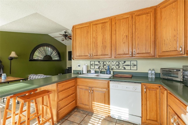 kitchen featuring sink, white dishwasher, ceiling fan, a textured ceiling, and vaulted ceiling