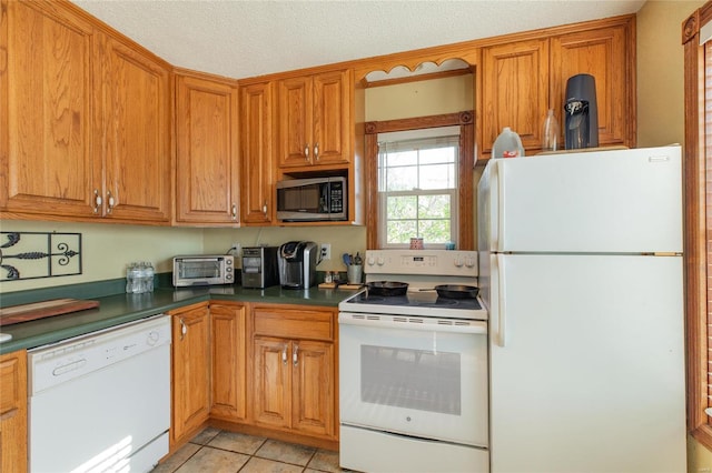 kitchen featuring white appliances, a textured ceiling, and light tile patterned floors