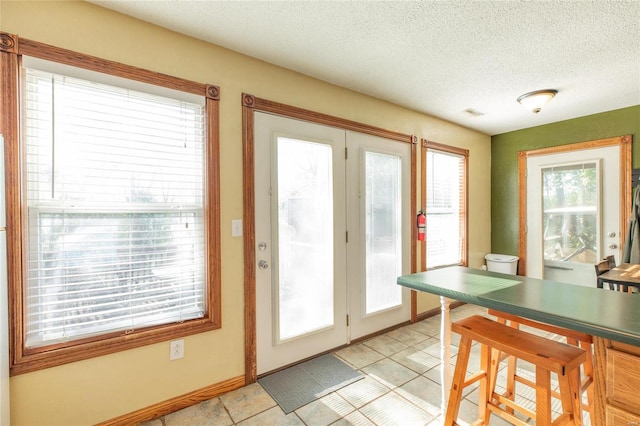 doorway to outside with a textured ceiling and plenty of natural light