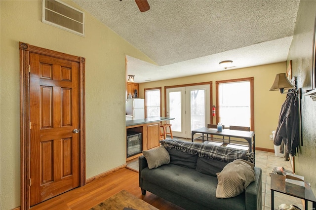 living room with a textured ceiling, light hardwood / wood-style floors, beverage cooler, lofted ceiling, and ceiling fan