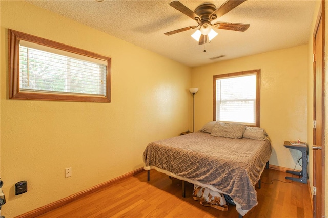 bedroom featuring hardwood / wood-style flooring, a textured ceiling, and ceiling fan