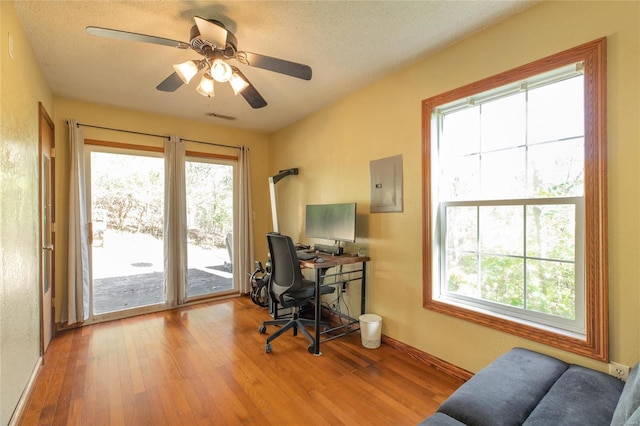 office area with electric panel, light hardwood / wood-style flooring, a textured ceiling, and ceiling fan