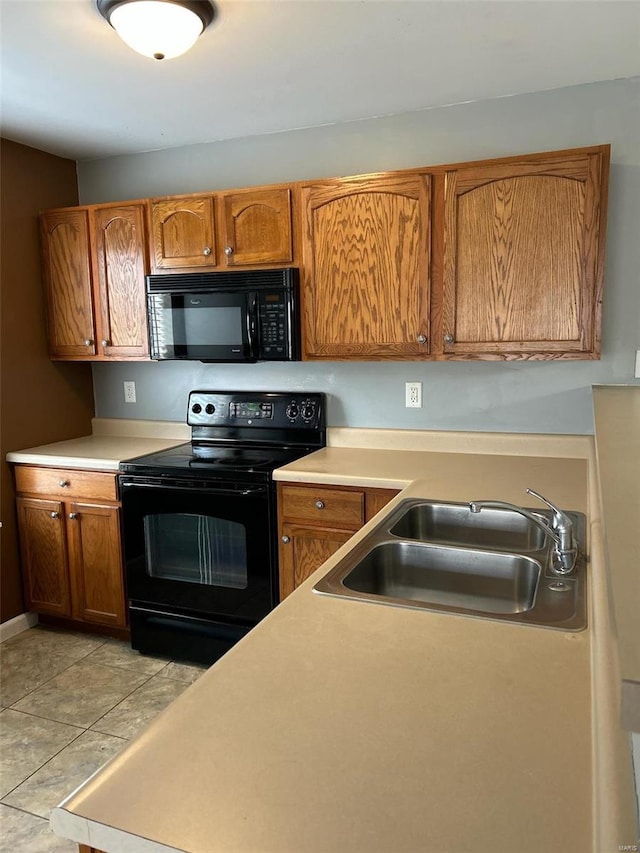 kitchen featuring sink, light tile patterned floors, and black appliances