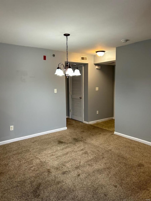 carpeted empty room with an inviting chandelier