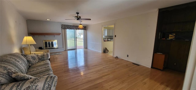 living room featuring light hardwood / wood-style flooring, ceiling fan, and ornamental molding