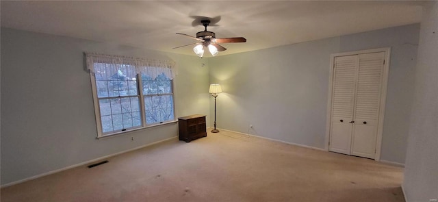 unfurnished bedroom with ceiling fan, light carpet, and a closet