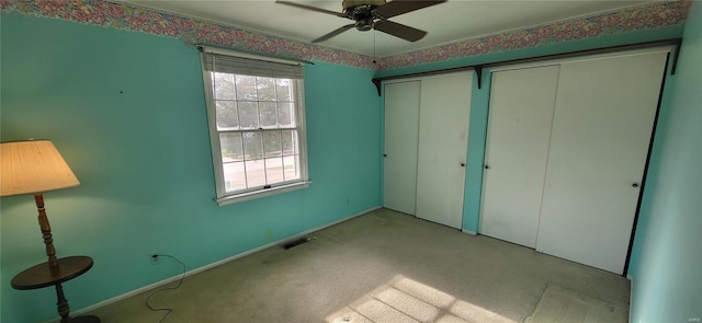 unfurnished bedroom featuring ceiling fan, light colored carpet, and two closets