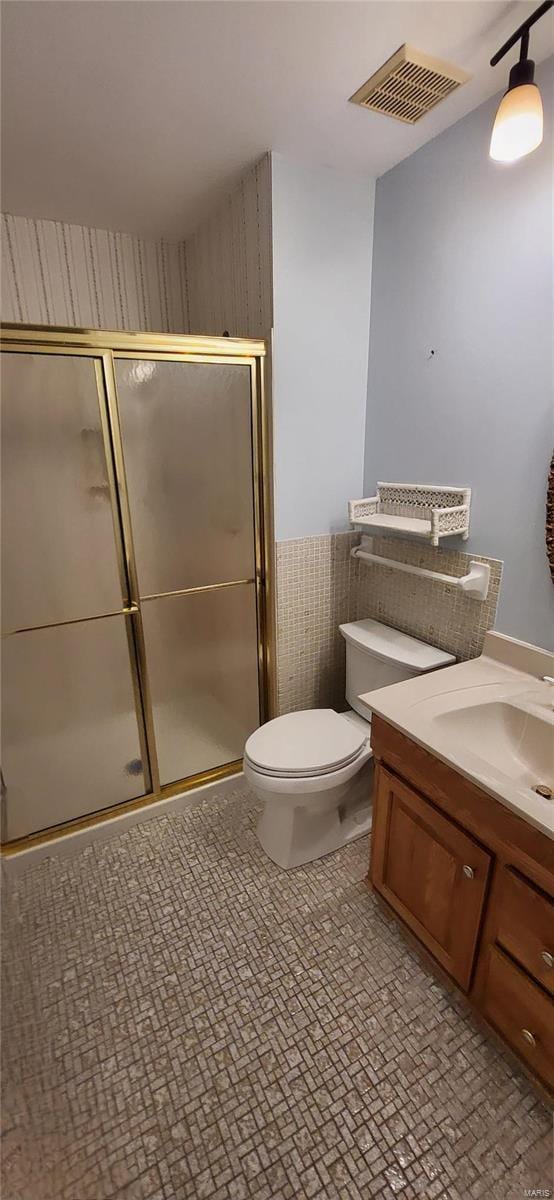 bathroom with vanity, toilet, and a shower with shower door