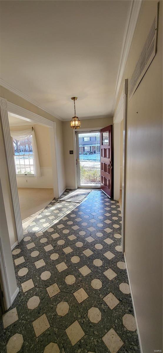 corridor featuring carpet, ornamental molding, a wealth of natural light, and a chandelier