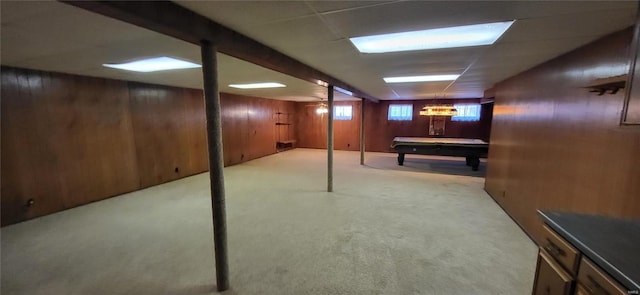 basement featuring pool table, a paneled ceiling, light colored carpet, and wooden walls