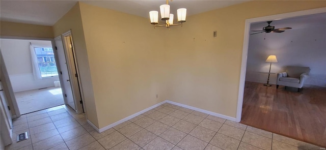 interior space with ceiling fan with notable chandelier and light wood-type flooring