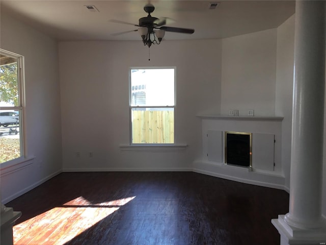 unfurnished living room with ceiling fan, ornate columns, and dark hardwood / wood-style flooring