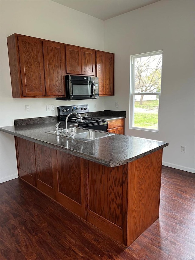 kitchen featuring dark hardwood / wood-style floors, stainless steel range with electric stovetop, and kitchen peninsula